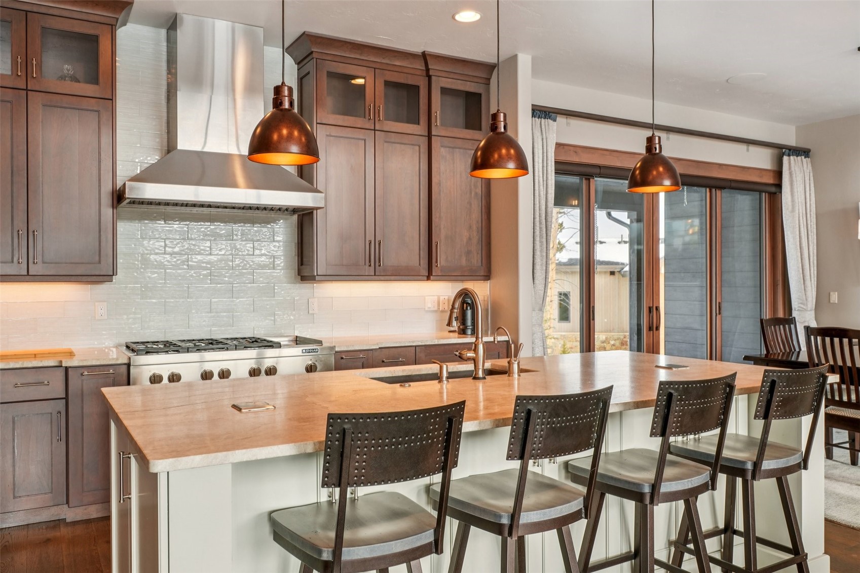 60 Barton Ridge Drive Breckenridge, CO 80424 - Photo 17 of 50 Kitchen featuring decorative light fixtures, glass fronted cabinets, a kitchen island with sink, decorative backsplash, and dark wood-style floors