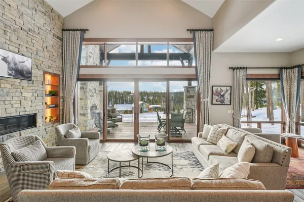 a living room with fireplace furniture and floor to ceiling windows