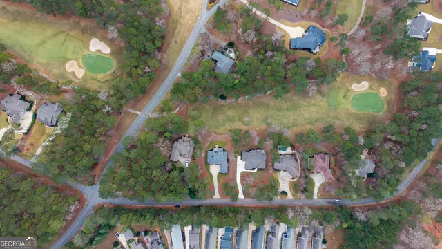an aerial view of a house with swimming pool and large trees