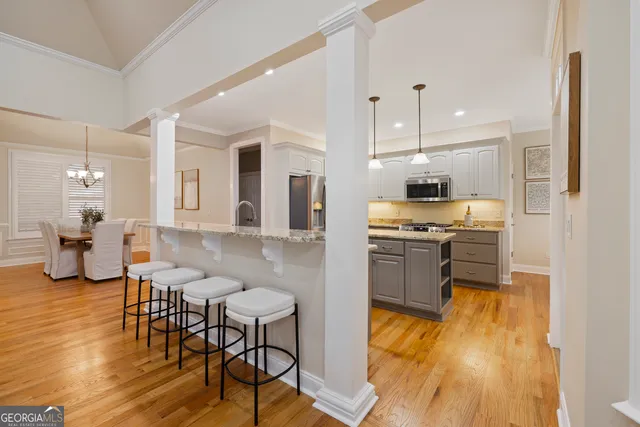 a kitchen with stainless steel appliances granite countertop a stove top oven a sink a refrigerator white cabinets and wooden floor