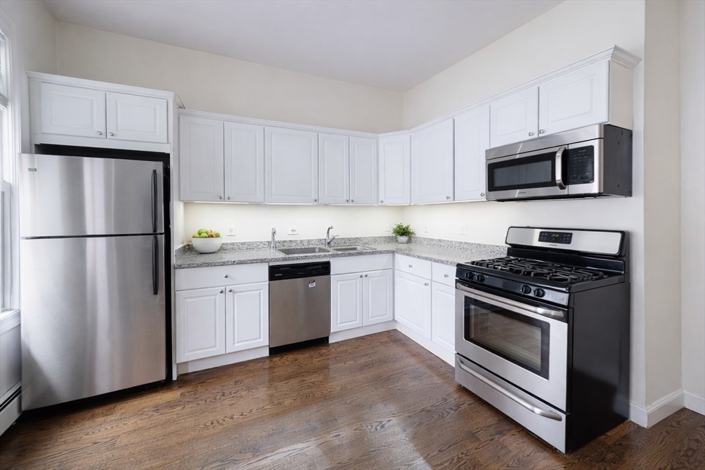11 Seckel Street, Unit 1 Cambridge, MA 02141 - Photo 4 of 21 a kitchen with granite countertop white cabinets and stainless steel appliances