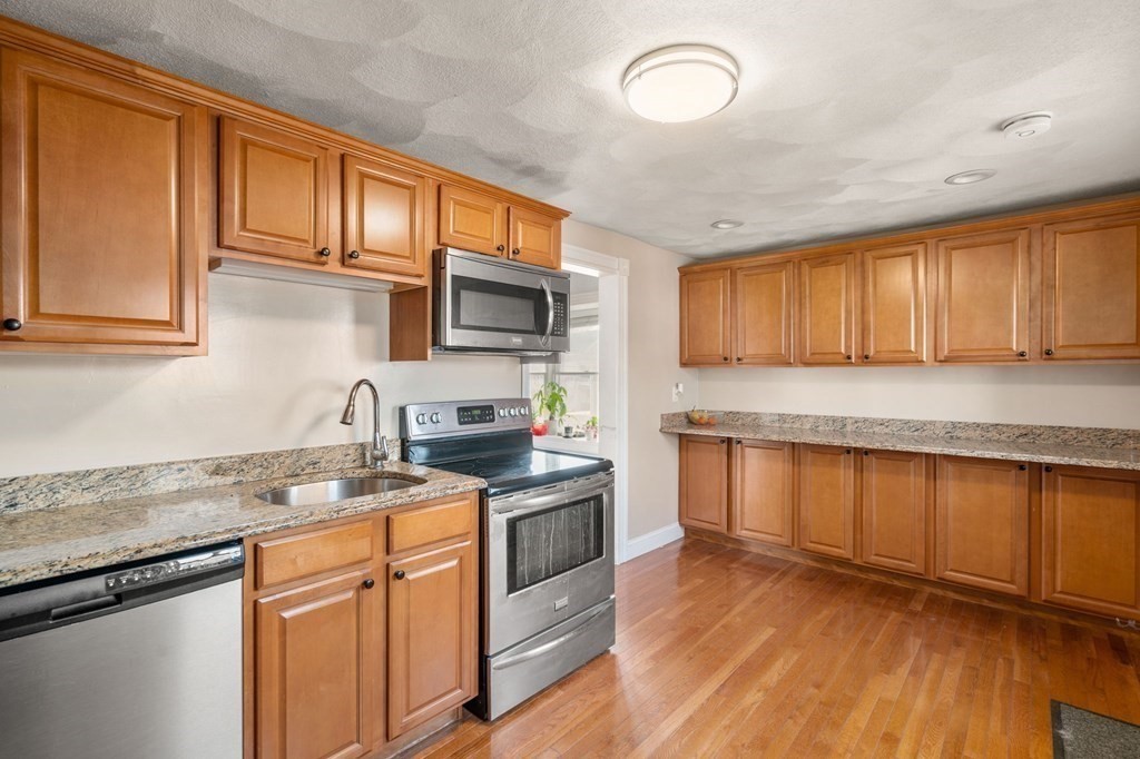 83 Cedar Street Wakefield, MA 01880 - Photo 5 of 36 a kitchen with stainless steel appliances granite countertop wooden cabinets a stove top oven a sink and dishwasher with wooden floor