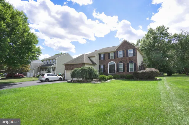 a view of a house with a big yard plants and large trees