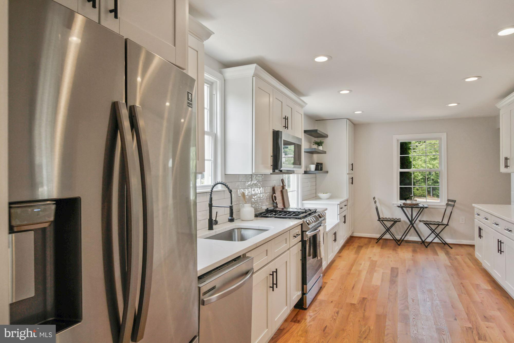 8112 Old Georgetown Road Bethesda, MD 20814 - Photo 13 of 51 a large kitchen with stainless steel appliances a refrigerator a sink dishwasher a stove and white cabinets with wooden floor
