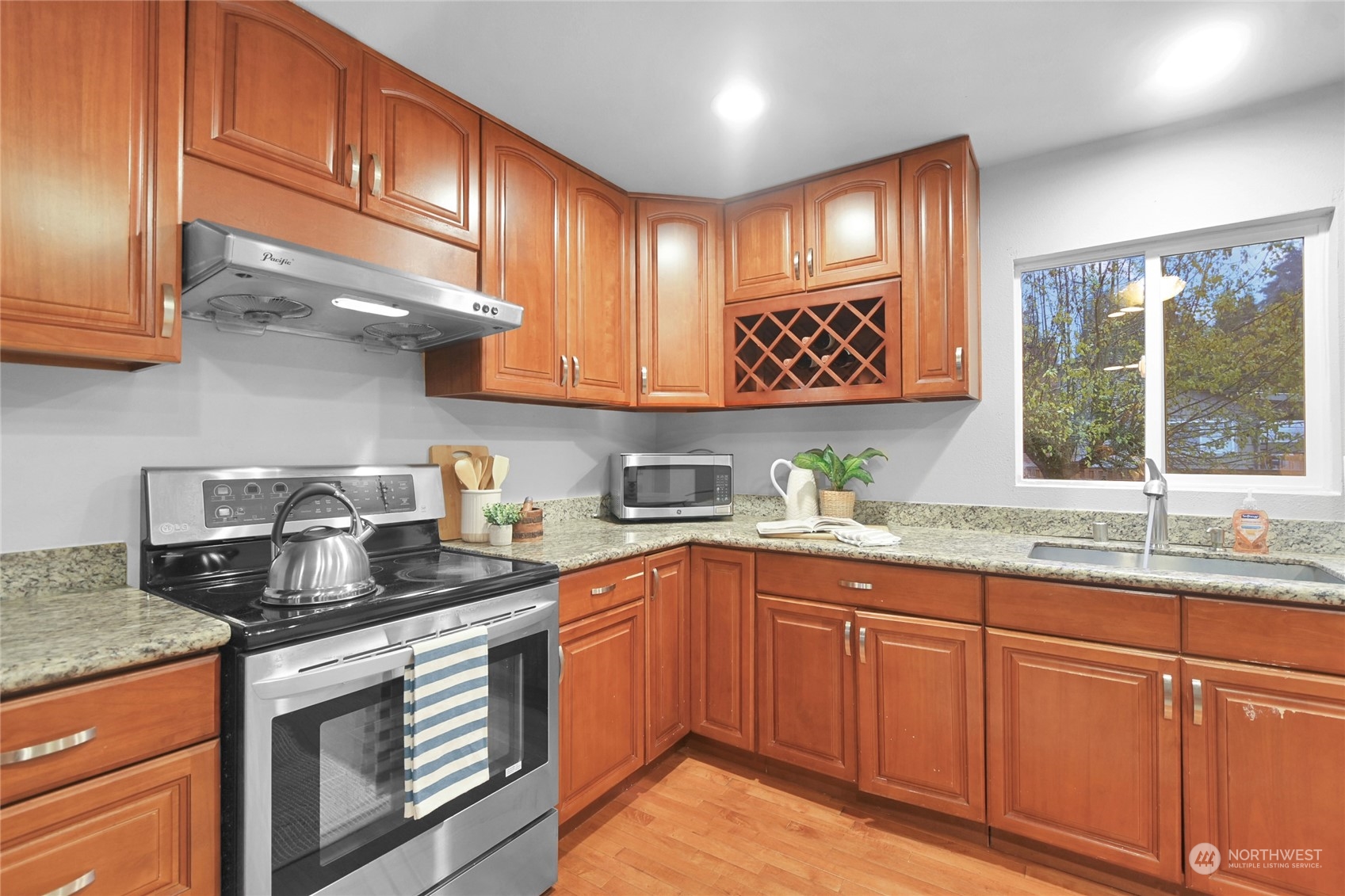 428 Southwest 124th Street Seattle, WA 98146 - Photo 11 of 28 a kitchen with granite countertop stainless steel appliances a sink stove and cabinets