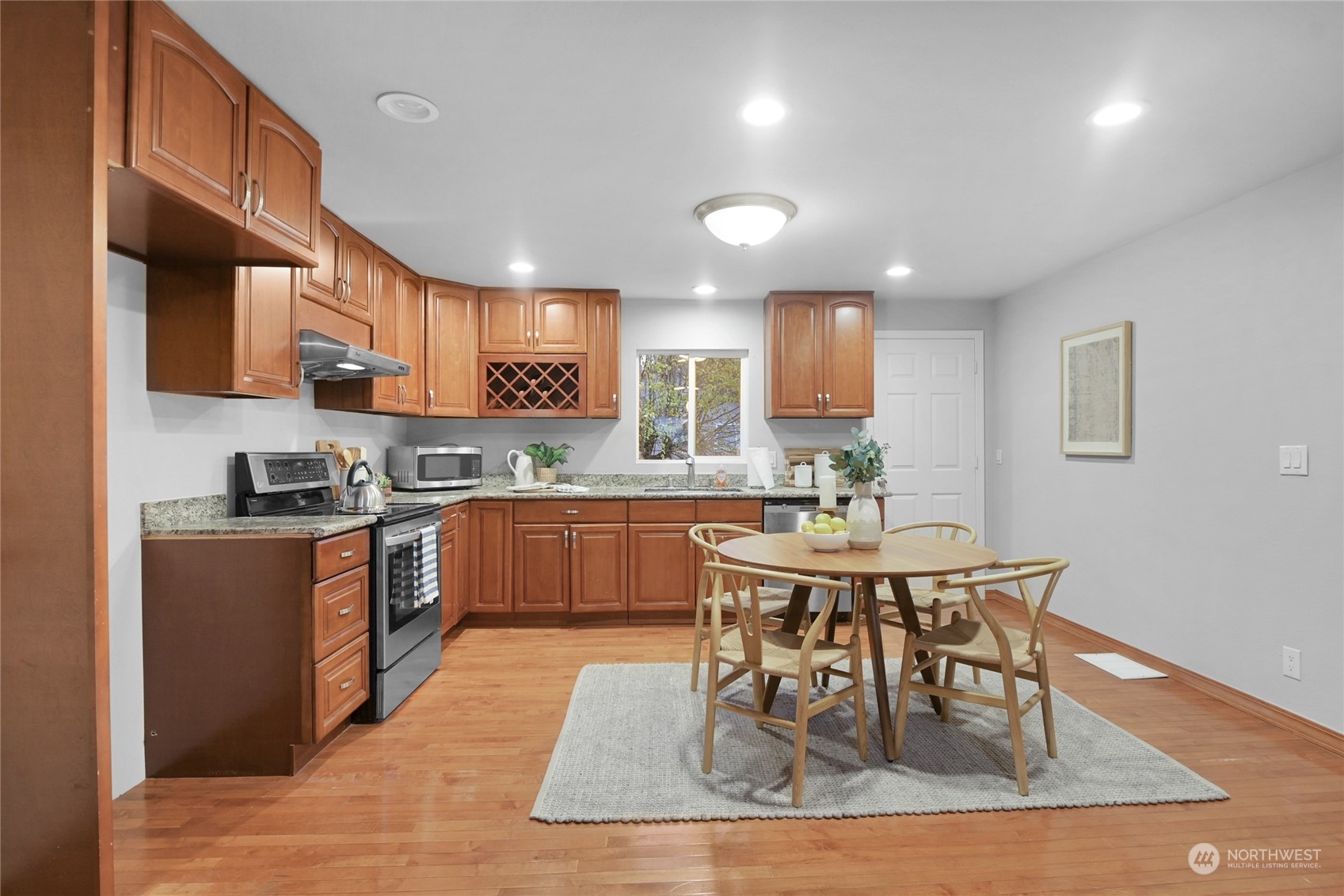 428 Southwest 124th Street Seattle, WA 98146 - Photo 9 of 28 a kitchen with stainless steel appliances granite countertop a stove a sink a microwave a dining table and chairs