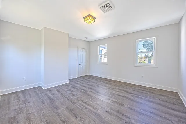 a view of an empty room with window and wooden floor