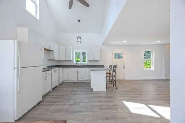 a large white kitchen with white cabinets and wooden floor