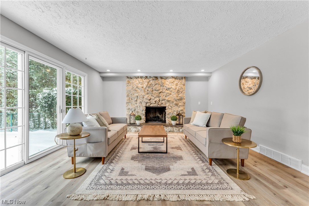 5025 Clubside Road Lyndhurst, OH 44124 - Photo 11 of 35 Living room with a textured ceiling, a fireplace, and light hardwood / wood-style floors
