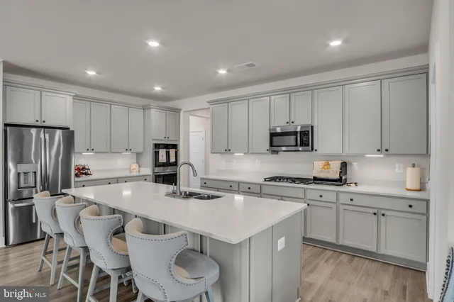 a kitchen with a sink a stove a refrigerator and white cabinets