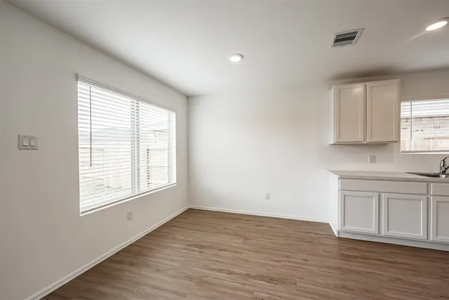 an empty room with wooden floor and windows