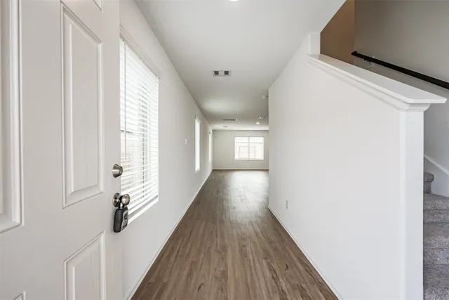 a view of a hallway with wooden floor and staircase