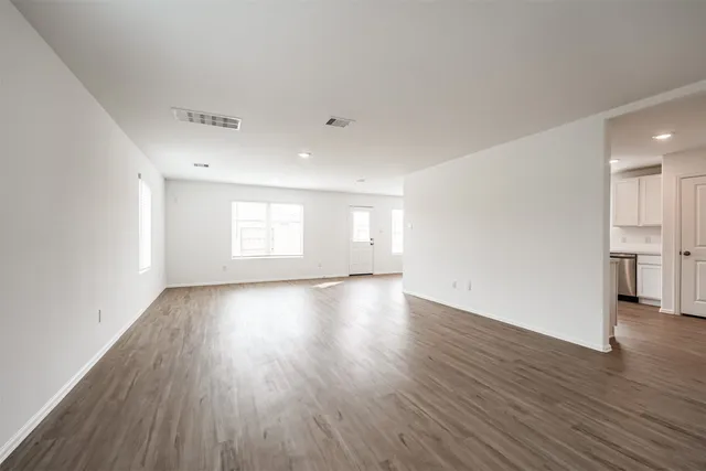 a view of empty room with wooden floor and window