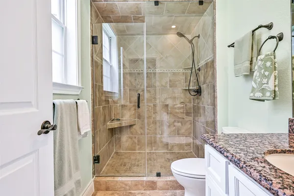 a bathroom with a granite countertop sink a toilet and shower