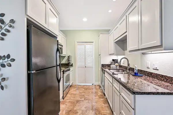 a kitchen with stainless steel appliances granite countertop a refrigerator a stove and a sink