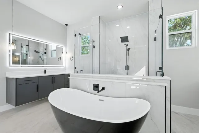 a spacious bathroom with a double vanity sink large mirror and bathtub