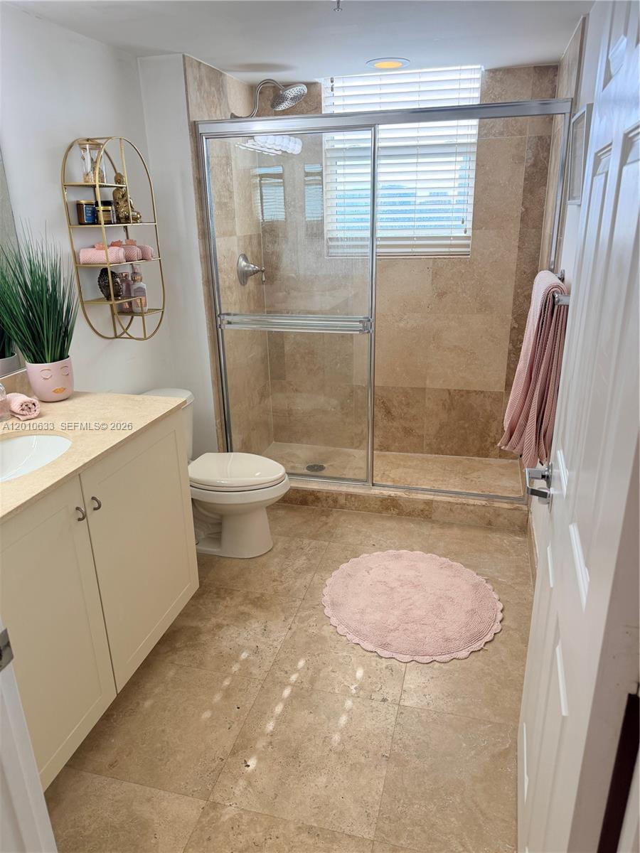 3232 Southwest 22nd Terrace, Unit 910 Miami, FL 33145 - Photo 17 of 31 a bathroom with a granite countertop sink a toilet a mirror and shower