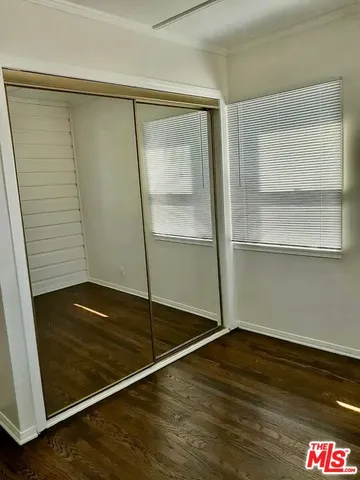 a view of an empty room with wooden floor and closet