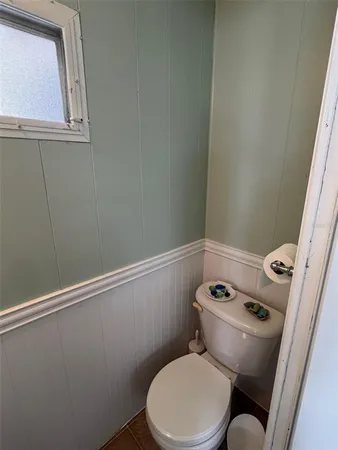 a white toilet sitting next to a small window