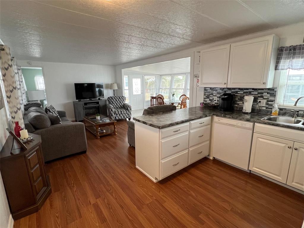 44 Thatch Palm Street West Largo, FL 33770 - Photo 6 of 25 a kitchen with stainless steel appliances granite countertop wooden floors a stove a microwave a sink and cabinets