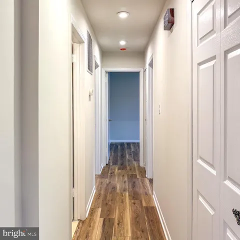 a view of a hallway with wooden floor and a bathroom