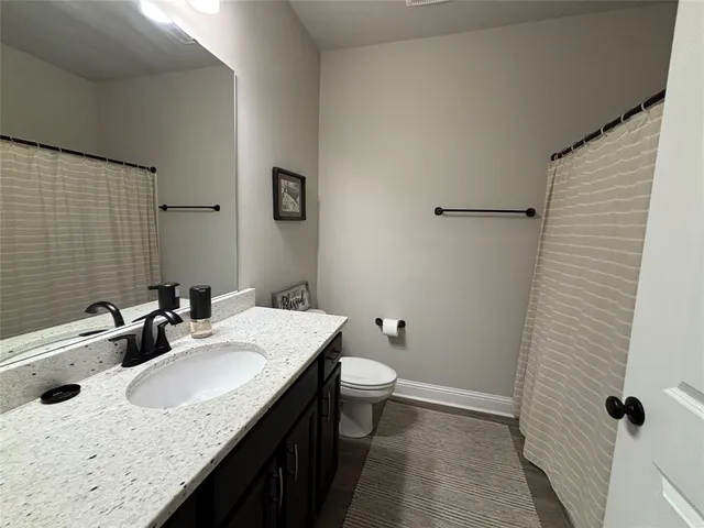 a bathroom with a granite countertop sink a toilet and mirror