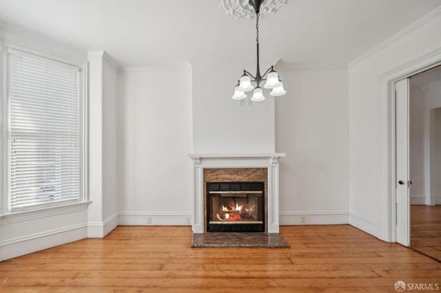 a view of an empty room with wooden floor fireplace and a window