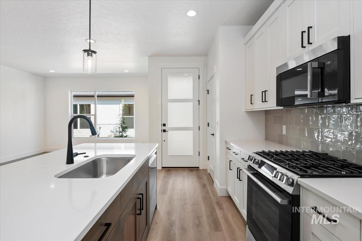 768 South Calhoun Lane Star, ID 83669 - Photo 14 of 36 Kitchen island with an undermount sink, a matte black faucet, and a pendant light