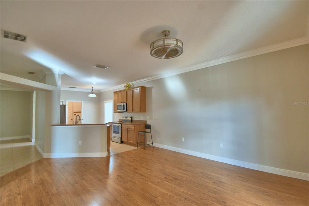 5610 Forest Ridge Drive Winter Haven, FL 33881 - Photo 18 of 70 an empty room with wooden floor and a kitchen
