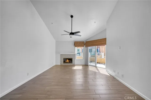 a view of an empty room with wooden floor fireplace and a window