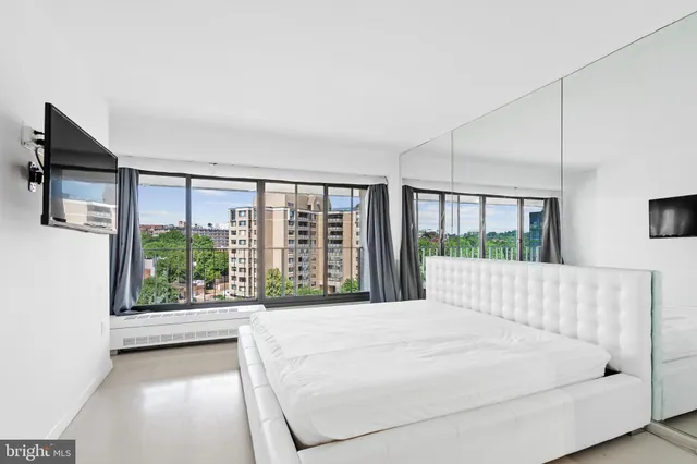 a large white bed sitting in a bedroom next to a large window