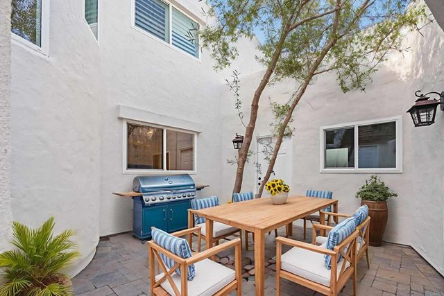 a kitchen with stainless steel appliances granite countertop a stove a refrigerator a sink a dining table and chairs with wooden floor