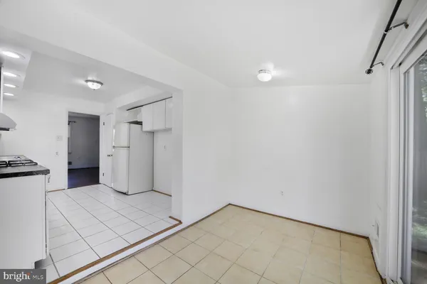 a view of a refrigerator in kitchen and an empty room