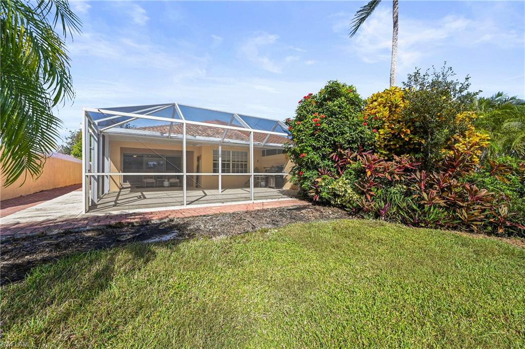 4910 Kingston Way Naples, FL 34119 - Photo 16 of 24 Back of property with a sunroom, glass enclosure, and a patio area