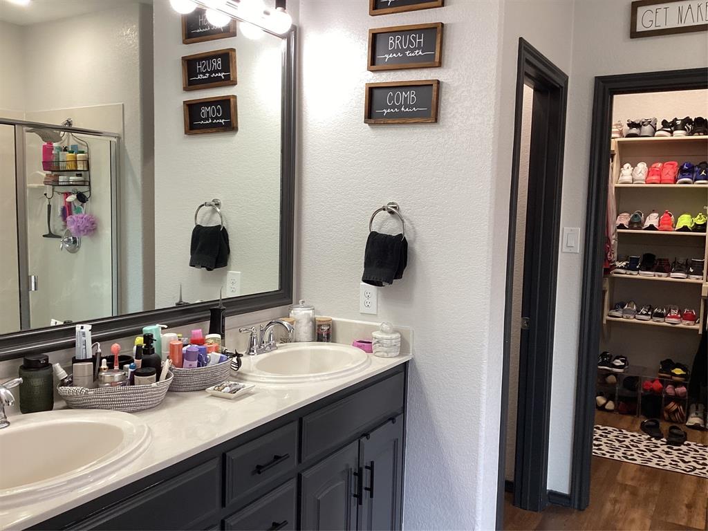 10320 Point Lobos Trail Fort Worth, TX 76177 - Photo 14 of 33 Bathroom featuring a dual vanity with undermount sinks and dark cabinetry, a spacious mirror, and a glass-enclosed shower