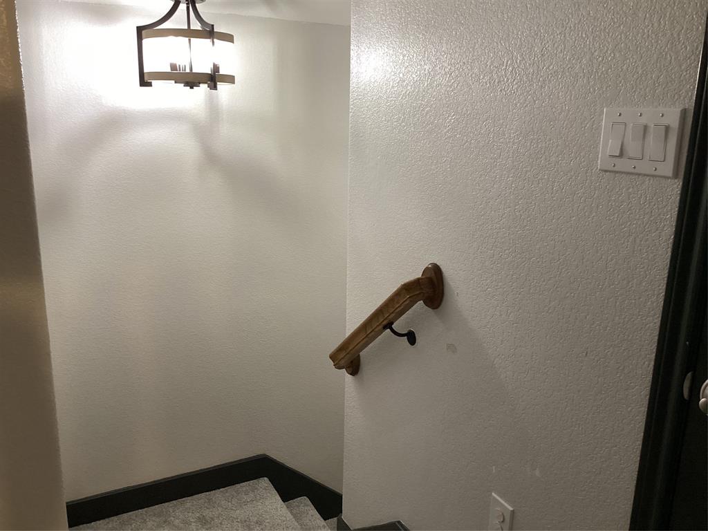 10320 Point Lobos Trail Fort Worth, TX 76177 - Photo 22 of 33 Stairwell featuring a contemporary semi-flush mount light fixture, textured walls, a wooden handrail, and carpeted steps with dark trim