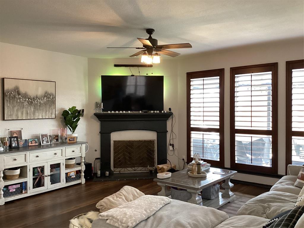 10320 Point Lobos Trail Fort Worth, TX 76177 - Photo 3 of 33 Living area featuring dark wood-finish flooring, a ceiling fan with integrated lighting, and multiple windows framed with dark wood trim
