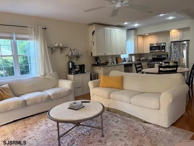 a living room with furniture a rug kitchen view and a large window
