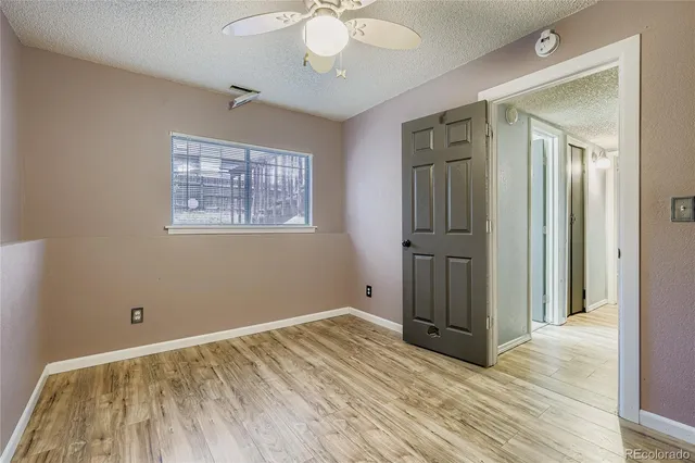 an empty room with wooden floor cabinet and windows