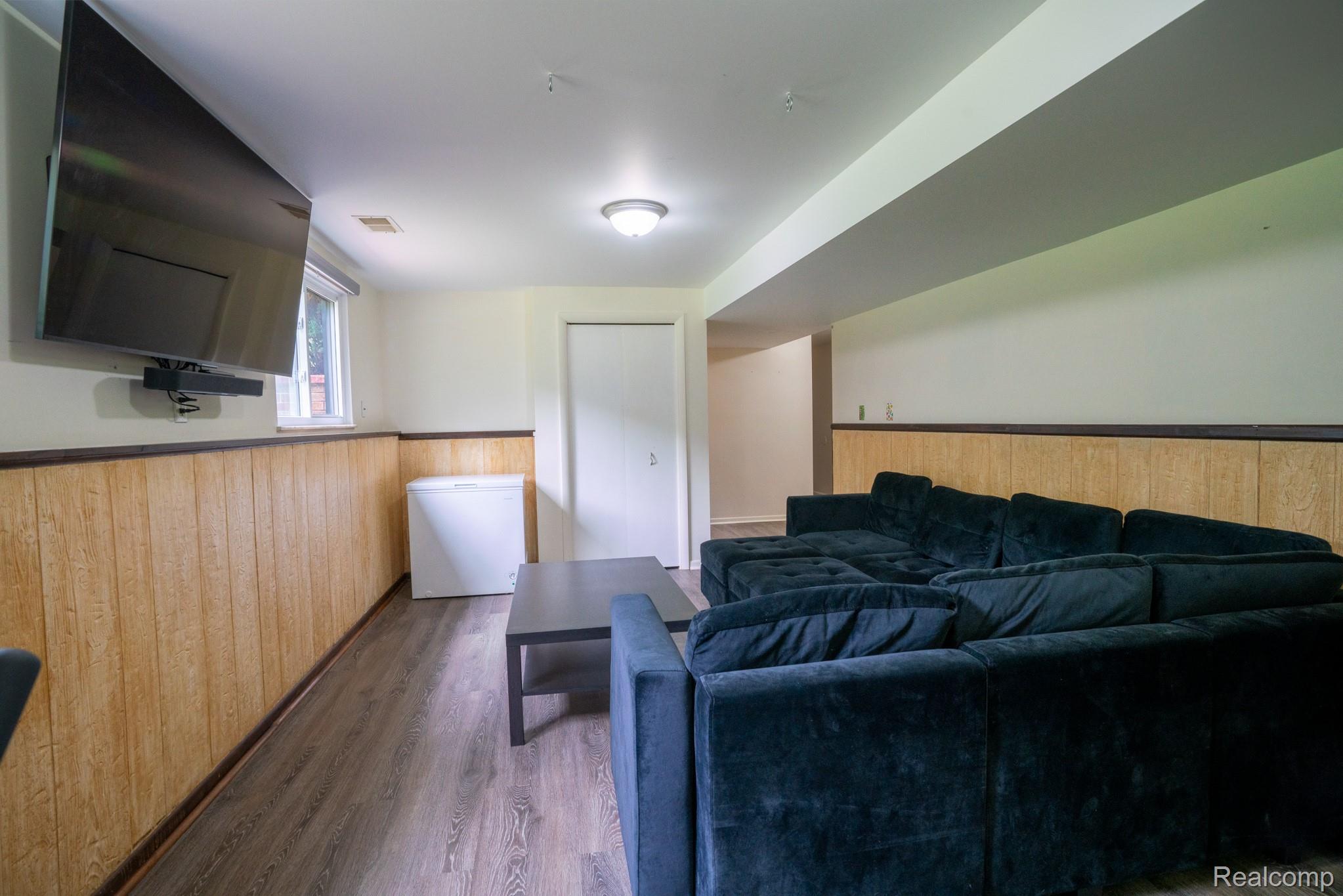 7333 Toma Road Dexter, MI 48130 - Photo 33 of 45 Recreational room featuring wood-finish paneling, a ceiling-mounted light fixture, and wood-finish flooring