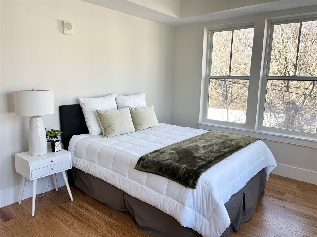 421 High Street, Unit 203 Medford, MA 02155 - Photo 11 of 19 a bedroom with a bed a lamp and a large window