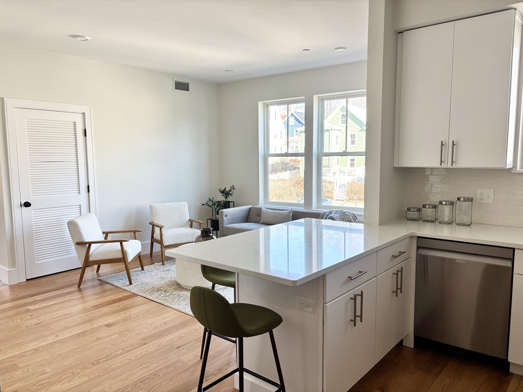 421 High Street, Unit 203 Medford, MA 02155 - Photo 4 of 19 a living room with stainless steel appliances granite countertop a sink dishwasher and white cabinets with wooden floor