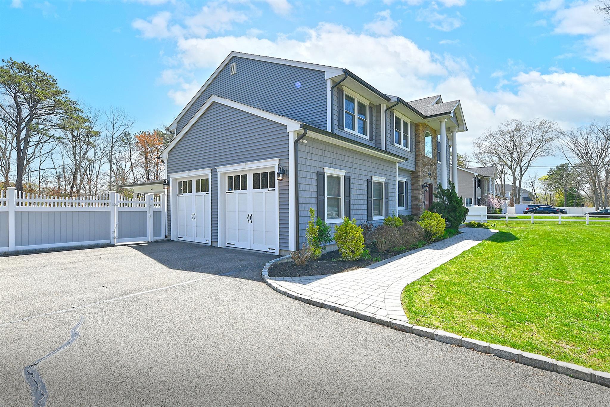 View of side of property featuring a lawn, fence, and aphalt driveway