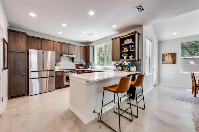 a kitchen with stainless steel appliances granite countertop a refrigerator and a stove top oven