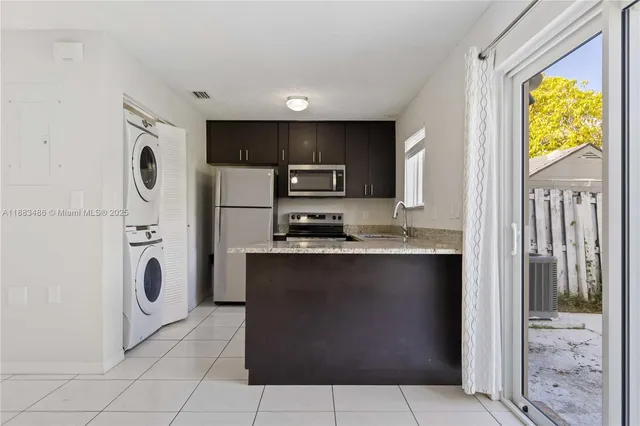 a view of kitchen island with stainless steel appliances granite countertop cabinets and a refrigerator