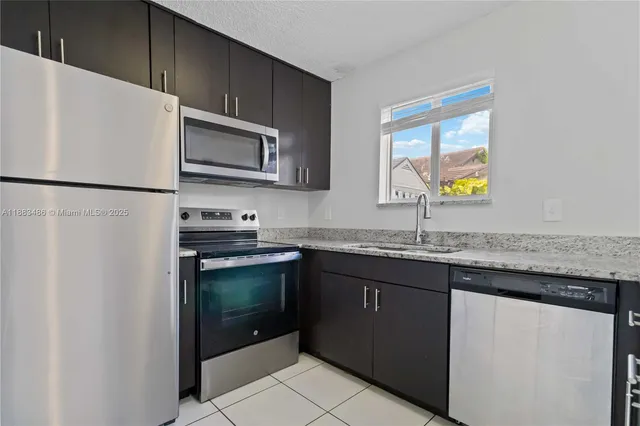 a kitchen with stainless steel appliances granite countertop a refrigerator a stove a sink and a microwave