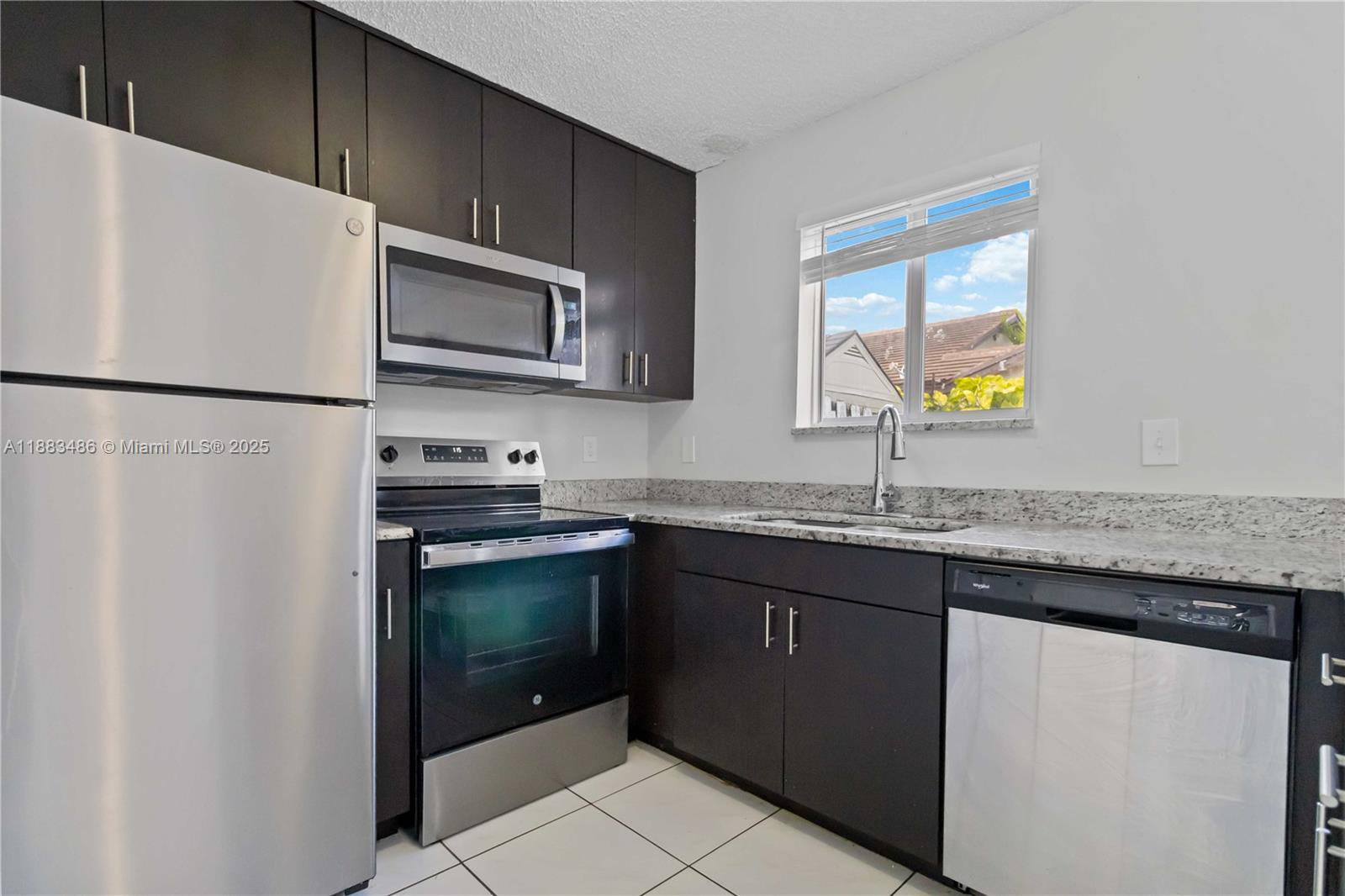 8431 Northwest 188th Terrace, Unit 8058 Hialeah, FL 33015 - Photo 13 of 34 a kitchen with stainless steel appliances granite countertop a refrigerator a stove a sink and a microwave