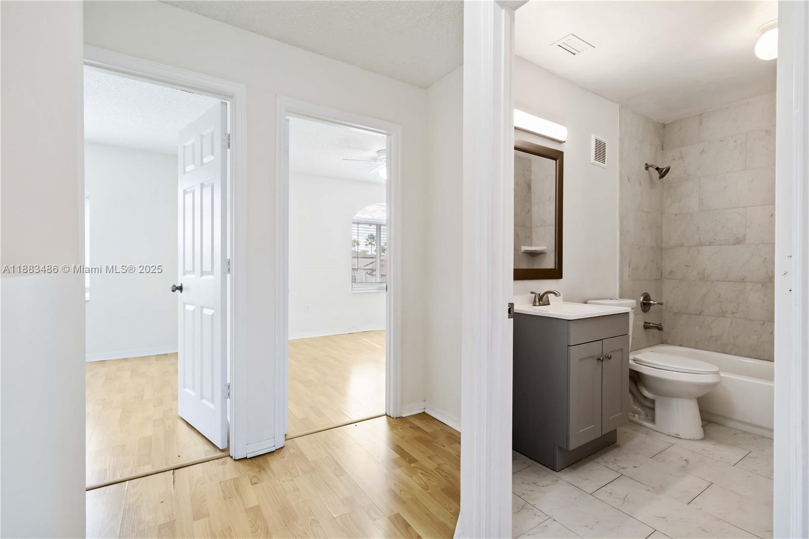 8431 Northwest 188th Terrace, Unit 8058 Hialeah, FL 33015 - Photo 17 of 34 a bathroom with a granite countertop toilet a sink and a mirror