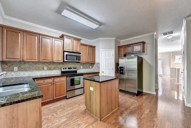 a kitchen with stainless steel appliances granite countertop a stove a sink and a microwave