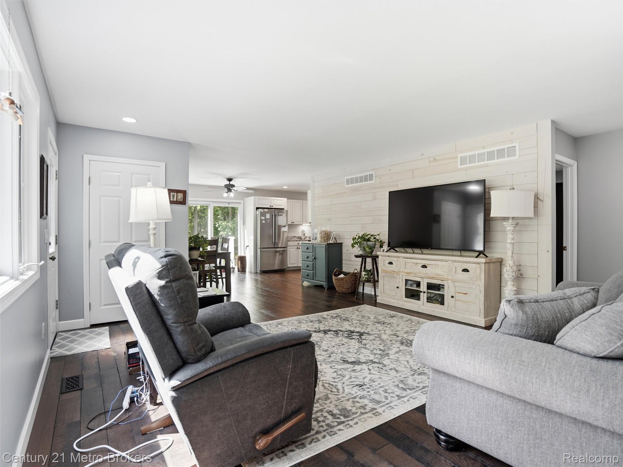 11447 North Latson Road Linden, MI 48451 - Photo 7 of 52 Spacious living area featuring wood-finish flooring, light grey painted walls, and a prominent shiplap accent wall